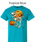 Skeleton T-Rex dinosaur Halloween t-shirt Tropical blue teal with skeleton dinosaur holding pumpkin candy bucket orange moon bats stars bright graphic tee
