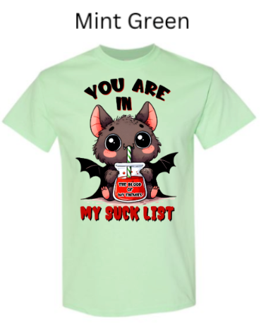 "Mint green t-shirt with cute vampire bat drinking from jar labeled 'The Blood of My Enemies,' 'You Are In My Suck List' text, big eyes, small wings, kawaii Halloween design"