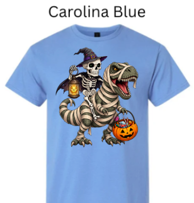 "Light carolina blue t-shirt displaying witch skeleton riding bandaged T-Rex, glowing pumpkins in hands, orange candy bucket, Halloween trick-or-treat dino illustration"