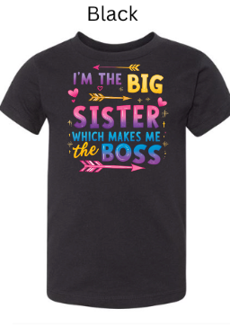 Black Bella+Canvas 3001T toddler tee featuring "I'M THE BIG SISTER WHICH MAKES ME BOSS" design. Vibrant gradient lettering with arrows and hearts popping against black. Bold big sister shirt.