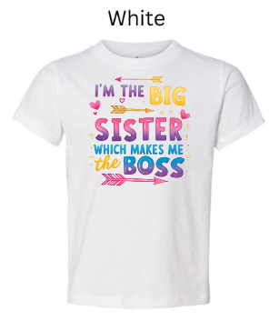 White Bella+Canvas 3001T toddler tee with "I'M THE BIG SISTER WHICH MAKES ME BOSS" design. Colorful gradient text with arrows and hearts on white. Big sister announcement shirt.